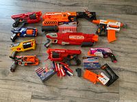 Overview of 8 Nerf blasters, multiple dart packs, and accessories arranged on floor.
