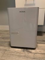 Front view of white Noma dehumidifier showing logo and body shape.