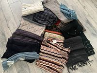 Overview photo showing 12 assorted scarves laid on floor in various colors and textures