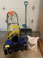 Front view of Snow Joe electric single-stage snow blower with yellow power cord coiled on handle.