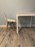 White George Oliver Lytle side chair next to white Ikea EKEDALEN table showing side profile of chair and table with wooden flooring and light wall.