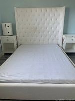 Full front view of upholstered twin bed with tall tufted headboard, showing mattress and frame upholstery.