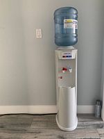 Front view of Livion water dispenser tower with blue water bottle on top, showing overall condition and size.