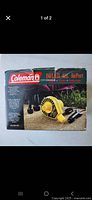Photo of the Coleman Inflate-All AirPort 12 Volt portable air pump original box showing branding and product image with camping background.
