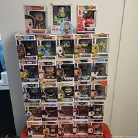 Full view of all Funko Pop figures arranged in five rows on a white surface with a red chair beneath