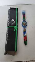 Full view of the wristwatch with original black box featuring Nightmare Before Christmas branding and green decorative stripe, showing the watch next to it.