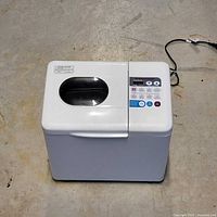 White Toastmaster bread maker with a lid that has a viewing window, control panel visible on top side.