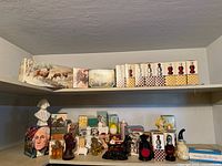 Photo showing shelf with 25+ vintage Avon perfume bottles and boxed gift sets. Bottles include animal shapes, character bust, and novelty designs in clear, amber, black, and red glass. Boxed sets with nature and animal artwork on packaging.