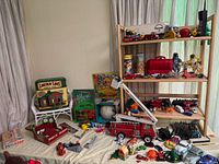 Wide image showing table with assorted vintage toys including Lincoln Logs, fire truck, mini cars, action figures, puzzles, and animal figurines.