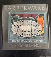 Box with Farberware branding and International Silver Company logo. Contains the silverplate expandable footed trivet.