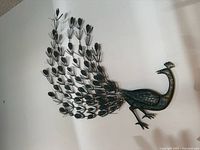 Metal peacock wall art sculpture mounted on a wall showing detailed tail design and body texture.