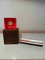 Both items displayed side by side: red acrylic paperweight with chip and wooden base, and clear acrylic desktop thermometer with corporate branding.
