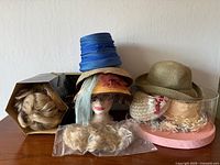 Overview of vintage hats and wigs in lot on tabletop