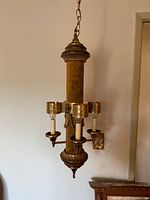 Full view of hanging chandelier showing three candle-style lights on a vertical cylinder with brown fabric and gilt metal accents.