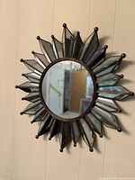 Front view of vintage mid century brass starburst mirror showing circular center mirror with surrounding pointed mirrored glass rays framed in brass with small ball tips.