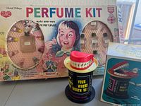 Vintage 1953 Lisbeth Whiting Perfume Kit in original box with colorful 1950s illustration and compartments containing small bottles and accessories.