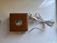 Top view of the walnut lighted display box showing the glass hole and attached white power cord with plug and in-line switch.