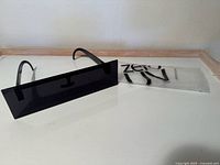 Front view of one pair of black zeroUV photo censorship style sunglasses with packaging pouch