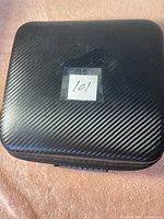 Closed black hard case with textured pattern and label '101'.