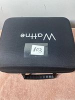 Closed hard carrying case with Wathne logo containing the body massager and accessories.