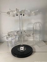 Front view of clear acrylic jewelry organizer with hooks, drawers, and black base