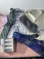 Overview of men's dress shirts in packaging, assorted silk ties, and boxed salt and pepper shakers