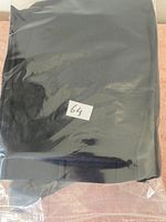 Suit pants folded and enclosed in plastic packaging with label number 64 visible.