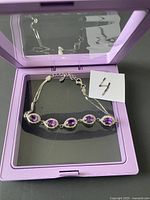 Silver amethyst bracelet displayed inside open purple box with mirror in lid.