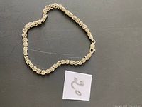 Silver bracelet and earrings laid flat on a gray surface with a white label.