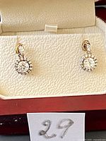 Photo of silver drop earrings displayed on a cream padded jewelry holder with white tag marked '29'