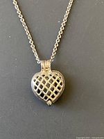 Front of the silver heart-shaped locket showing lattice design on pendant.