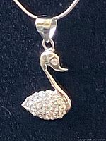Close-up of the silver swan pendant necklace showing rhinestone details on body and eye.