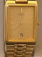 Close-up of the gold-tone rectangular Seiko watch face with date window.