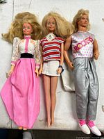 Front view of all three dolls with outfits and accessories visible