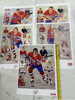 Three posters laid out showing full artwork and measuring tape for scale