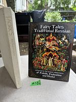 Two hardcover books standing side by side, one titled 'Fairy Tales Traditional Russian' with colorful folklore art on the cover, the other titled 'Faeries' with a plain off-white spine and gold embossed text.