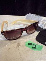 Close-up of one pair of men's sunglasses with brown gradient lenses and light beige arms