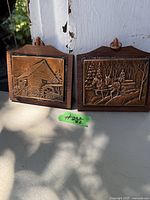 Pair of vintage copper wall art pieces framed in wood hanging on wall showing rustic water mill and a logging scene
