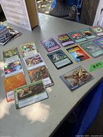 Photo showing a group of trading cards laid out on a table including green, purple, and orange colored cards as well as some with fantasy art and game information.
