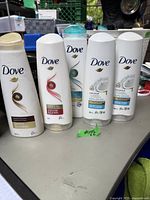 Five bottles of Dove shampoo in various formulations, mostly full, displayed on a table.