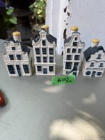 Front view of the four blue and white ceramic Delft houses by Bols for KLM, showing various Dutch gable roof designs and window details.