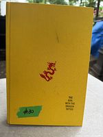 Front cover of yellow textured hardcover book with small red dragon and title The Girl with the Dragon Tattoo