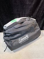Full view of the packed mattress inside the black Coleman branded carry bag with shoulder strap.