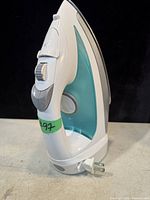 Side view of the Hamilton Beach iron showing white and teal body, handle, and control dial.