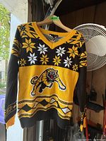 Front view of the Hamilton Tiger-Cats sweater showing tiger logo, snowflake patterns, and V-neck collar.