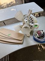 White Hunter ceiling fan with three frosted glass lights, four light wood blades, wiring and mounting hardware on white table.