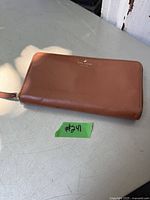 Closed view of the brown leather Kate Spade wallet showing texture and logo