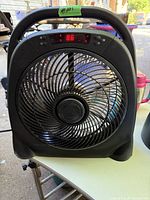 Photo of a black Konwin fan with a digital display showing '88' and several control buttons on the front. Fan is placed on a table.