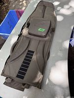 Top view of the brown rifle case showing the zippered pocket, handle, and durable zippers.