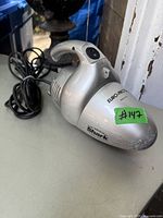 Silver Shark Euro-Pro 700 watts handheld vacuum cleaner with attached long black power cord laid on a surface showing wear and power button.